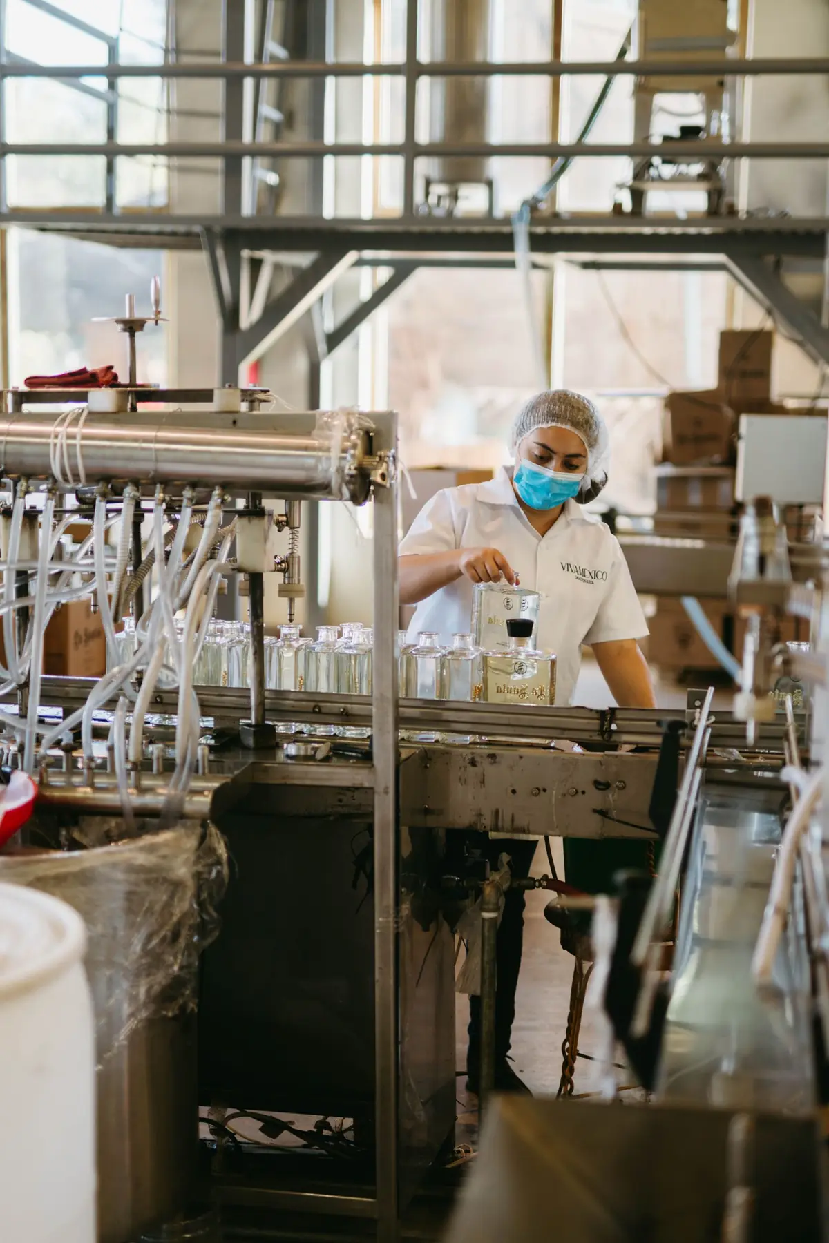 Operator in a hair net filling bottles on a production line