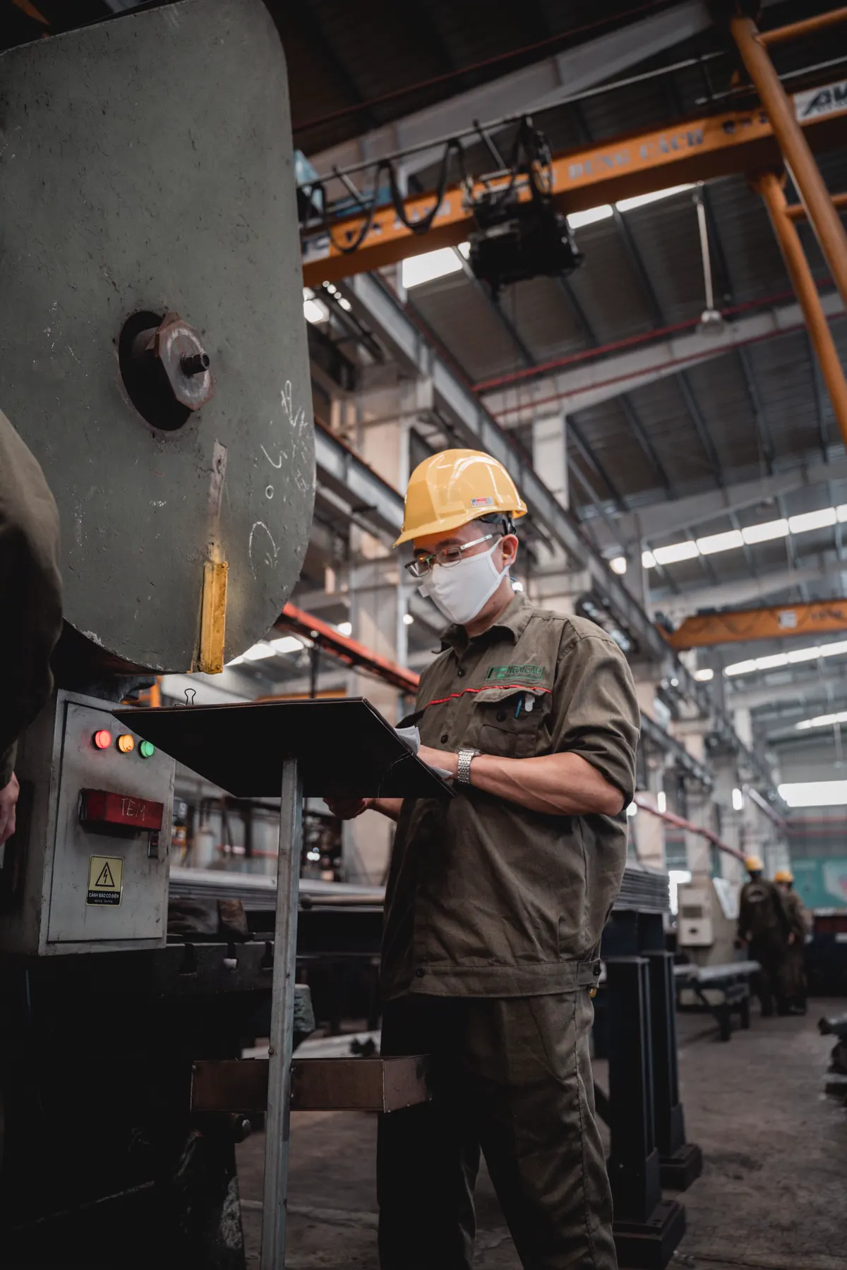 Engineer in a hard hat checking a machine on the factory floor