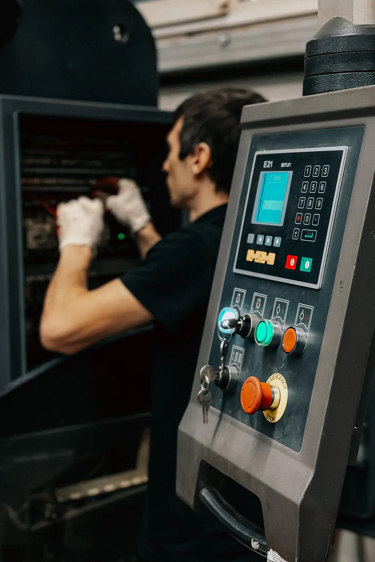 Technician working in an electrical cabinet beside a machine control panel